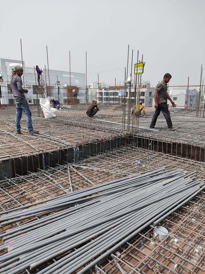 Workers engaged in construction on a building site, laying metal frameworks.