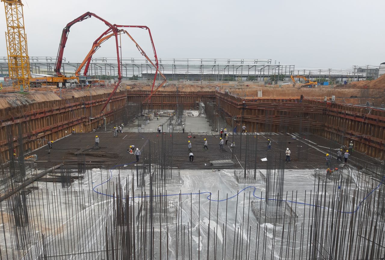 Construction site with workers setting foundation and steel reinforcements.