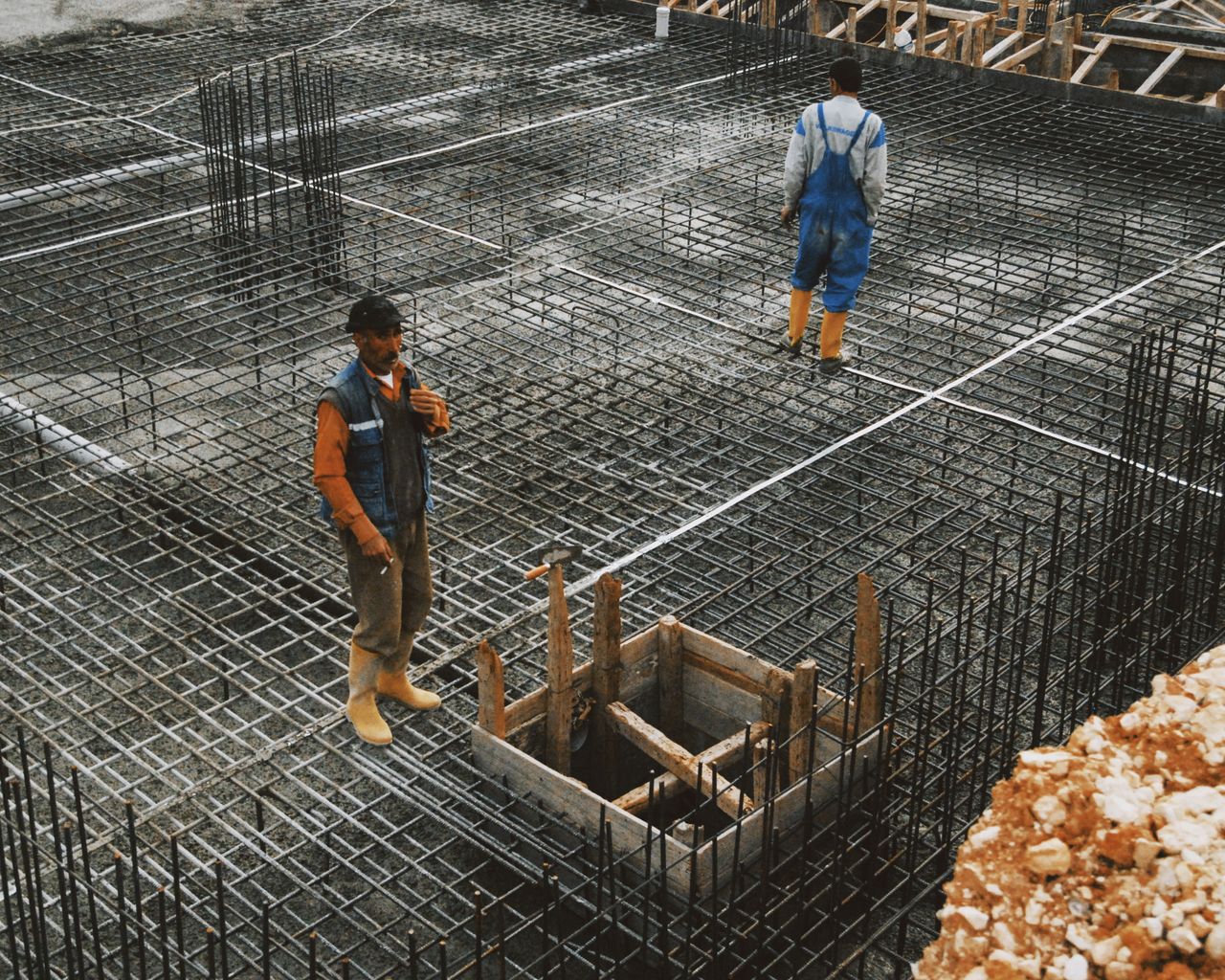 Workers preparing steel reinforcement at a construction site for concrete foundation.